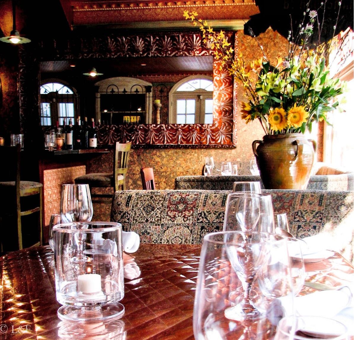The dining room: copper table, candle, gilt mirror and the bar